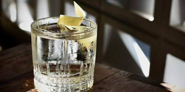 Drinque de gin servido no balcão do Zimbro, com luz filtrada pelo cobogó